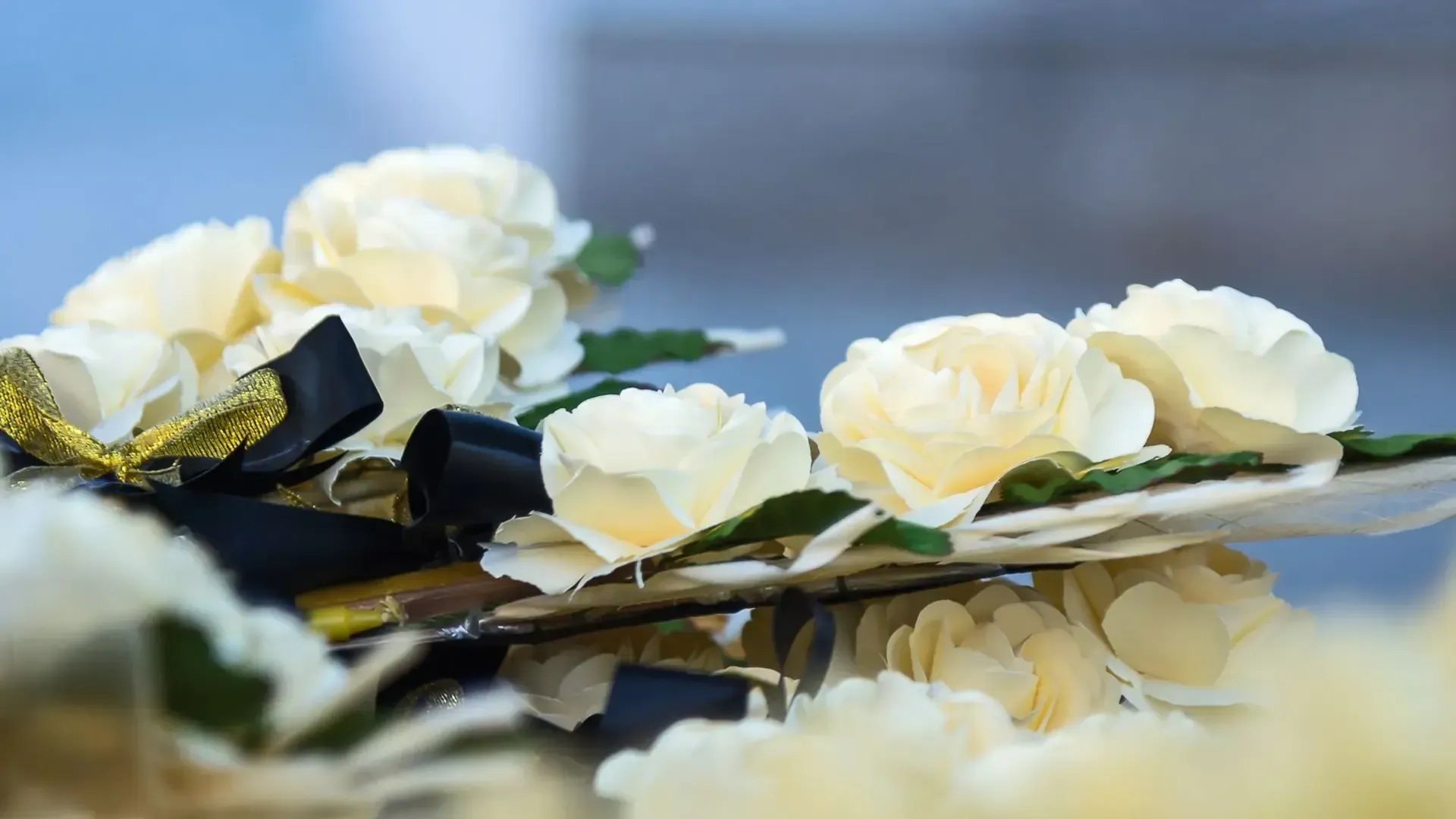 White flowers with black ribbon on reflective surface.