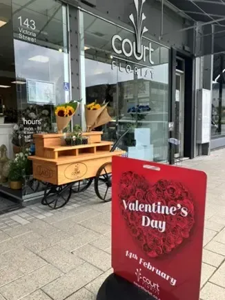 A valentine 's day sign is in front of a flower shop.