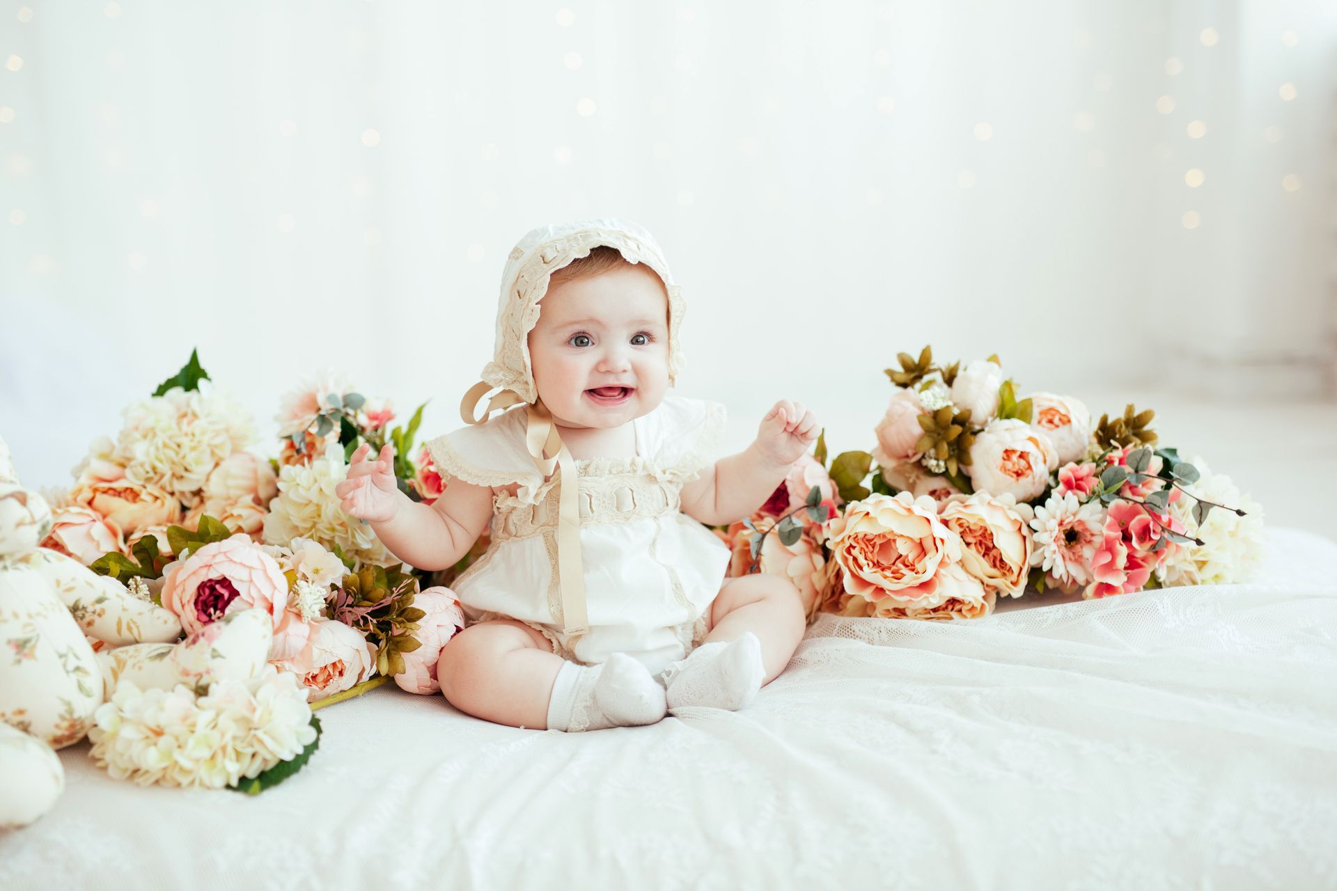 a baby girl is sitting on a bed surrounded by flowers .