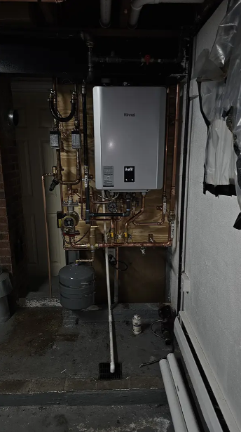 Utility room with a wall-mounted boiler, exposed pipes, and a concrete floor.