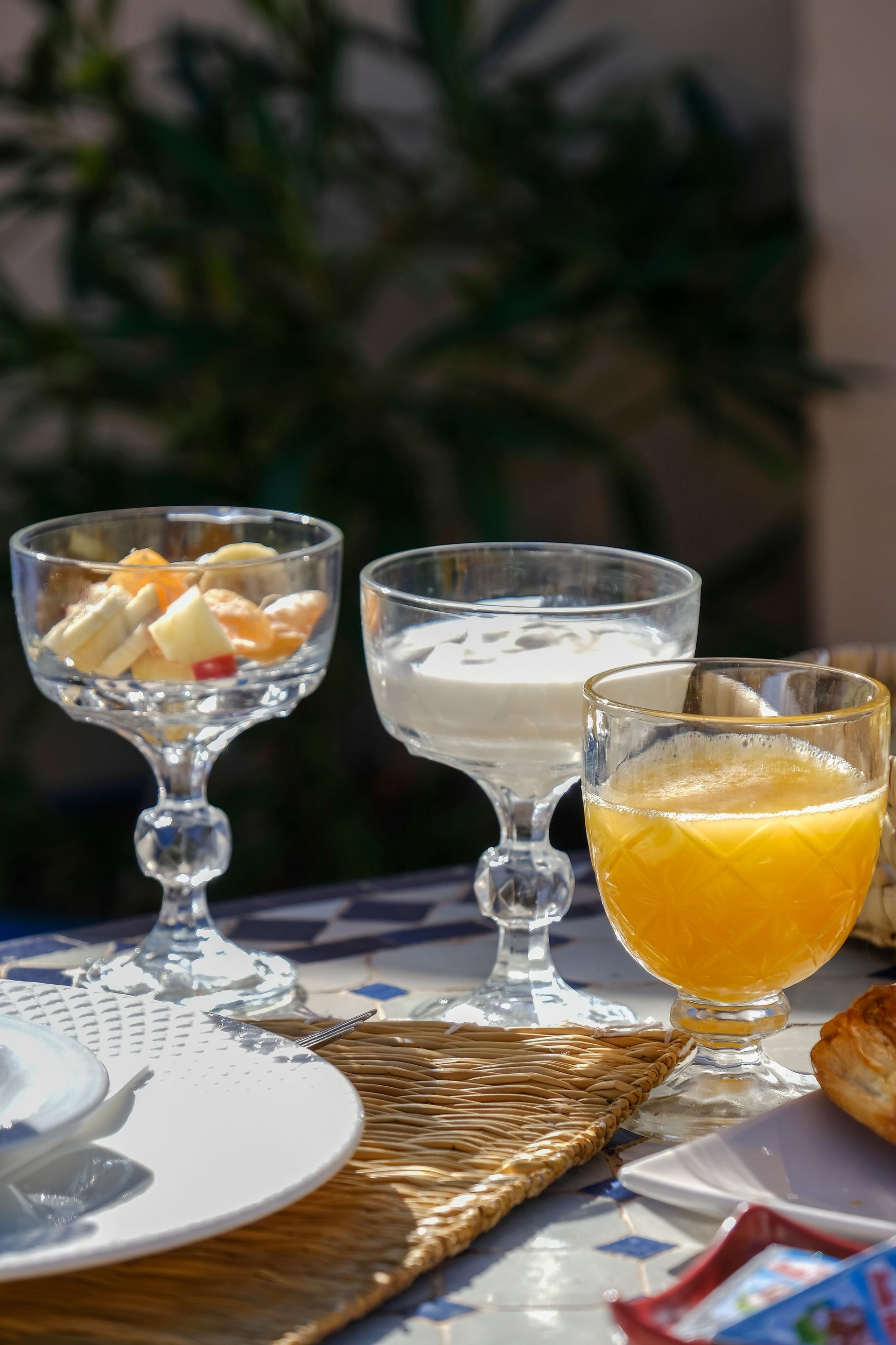 Breakfast table with fruit, yogurt, and orange juice in stemmed glasses.
