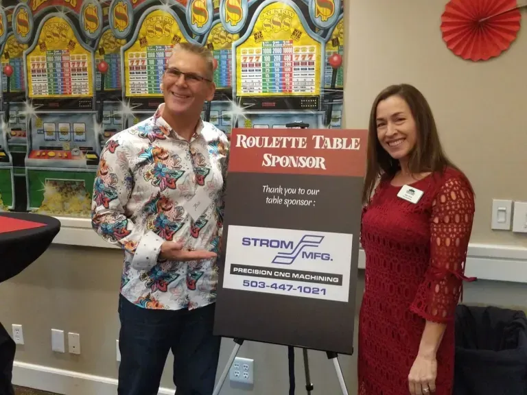 A man and woman standing next to a sign that says roulette table sponsor