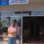 Two people are standing in front of a pepsi cola store.