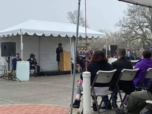 A woman is giving a speech in front of a crowd under a tent.