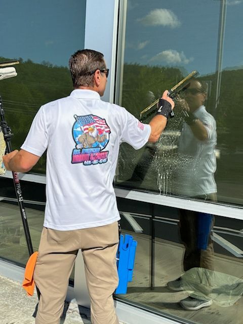 A man in a white shirt is cleaning a window.