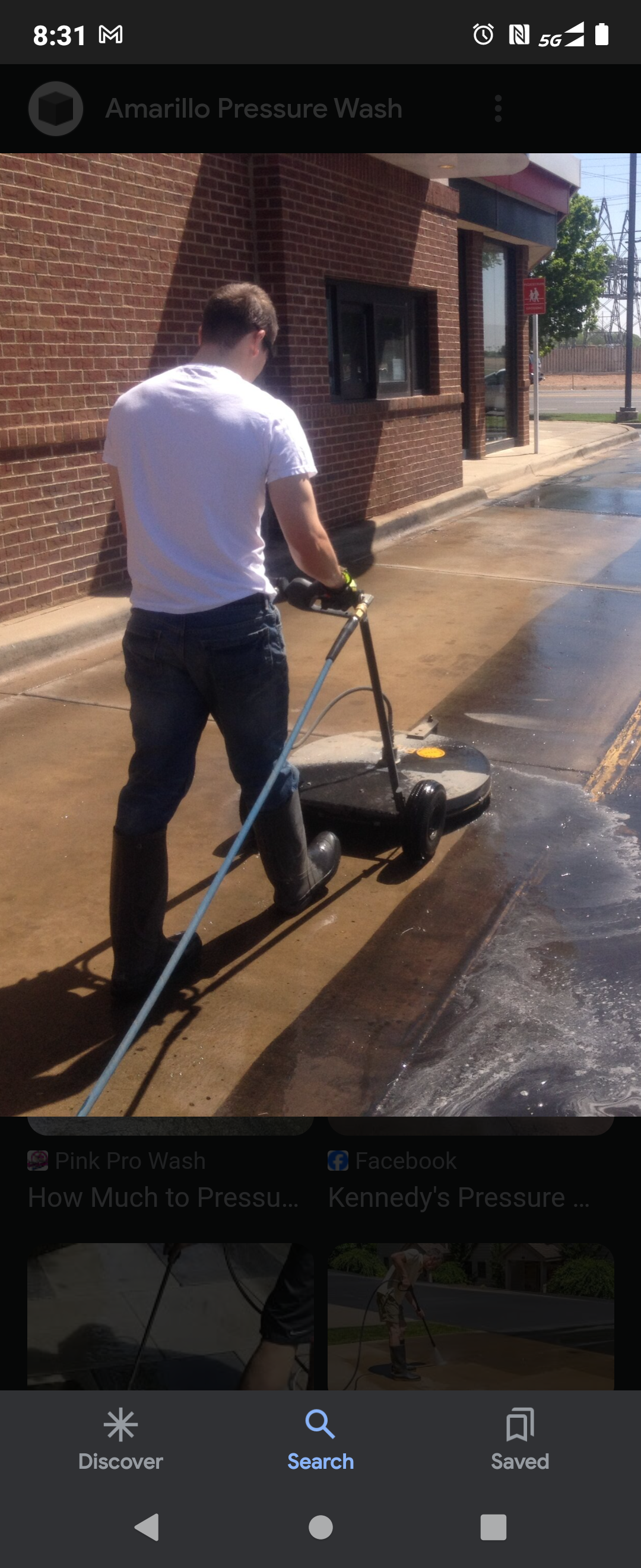 A man is cleaning the sidewalk with a machine.
