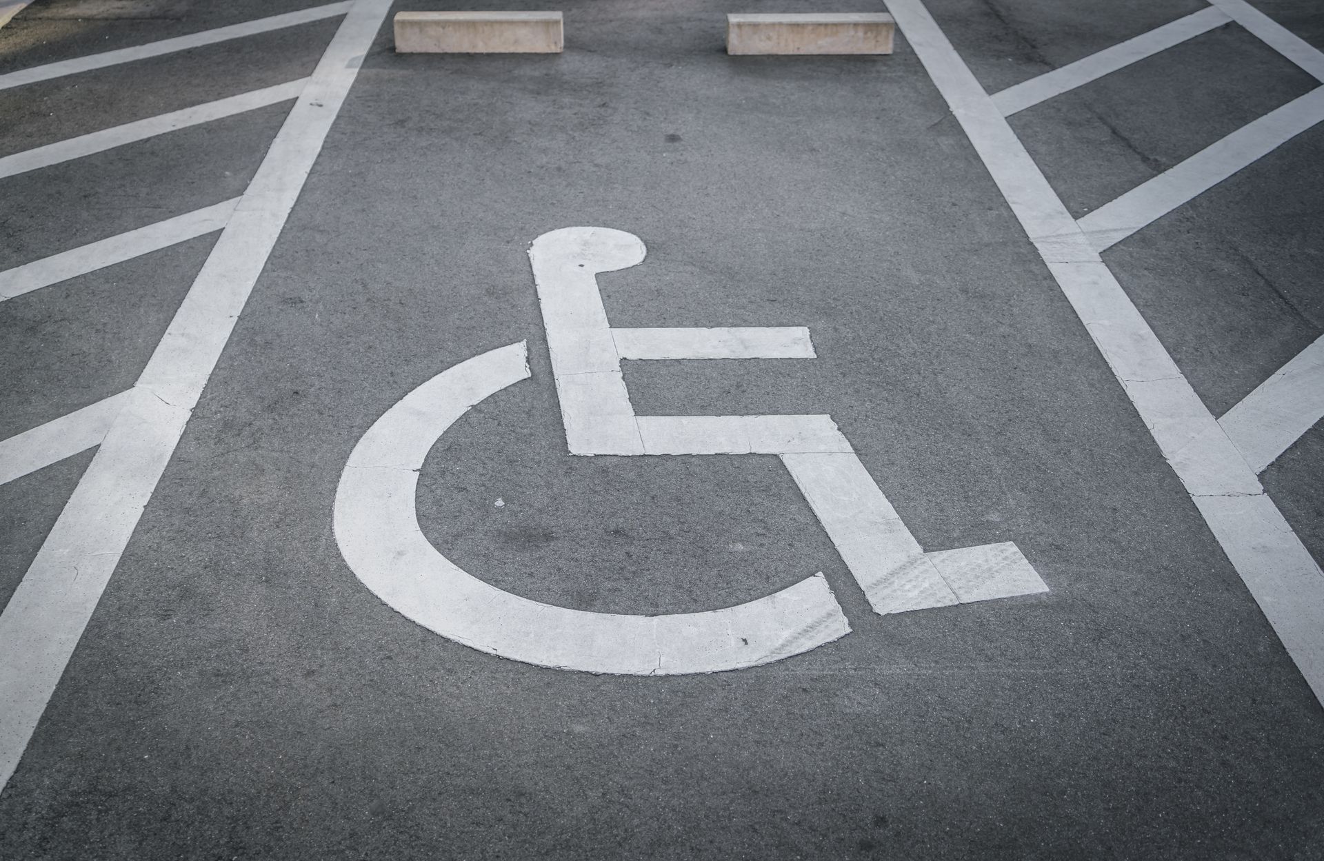 Accessible parking space with white wheelchair symbol painted on asphalt.