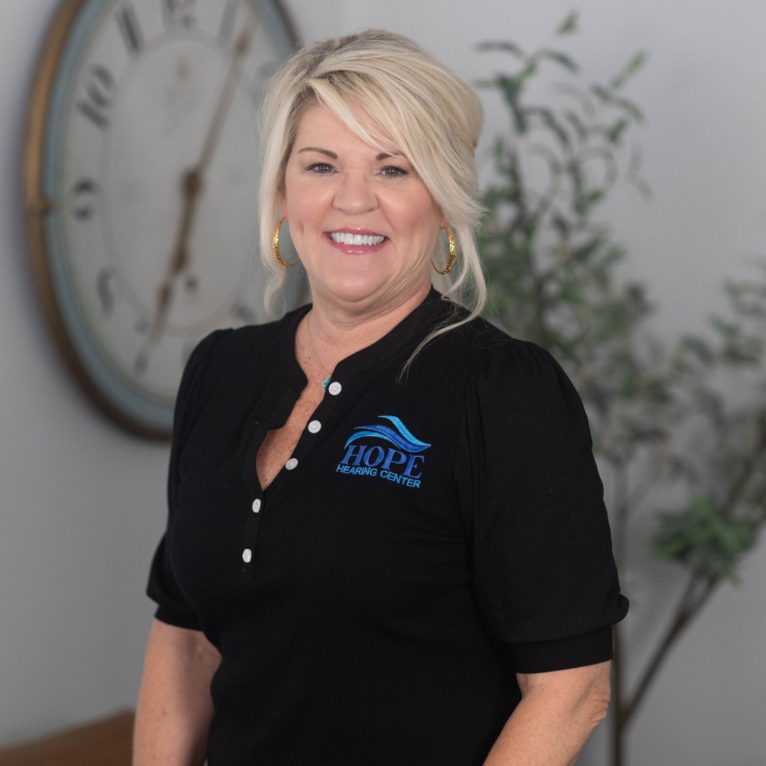 A woman wearing a black shirt with a butterfly on the front is smiling for the camera.