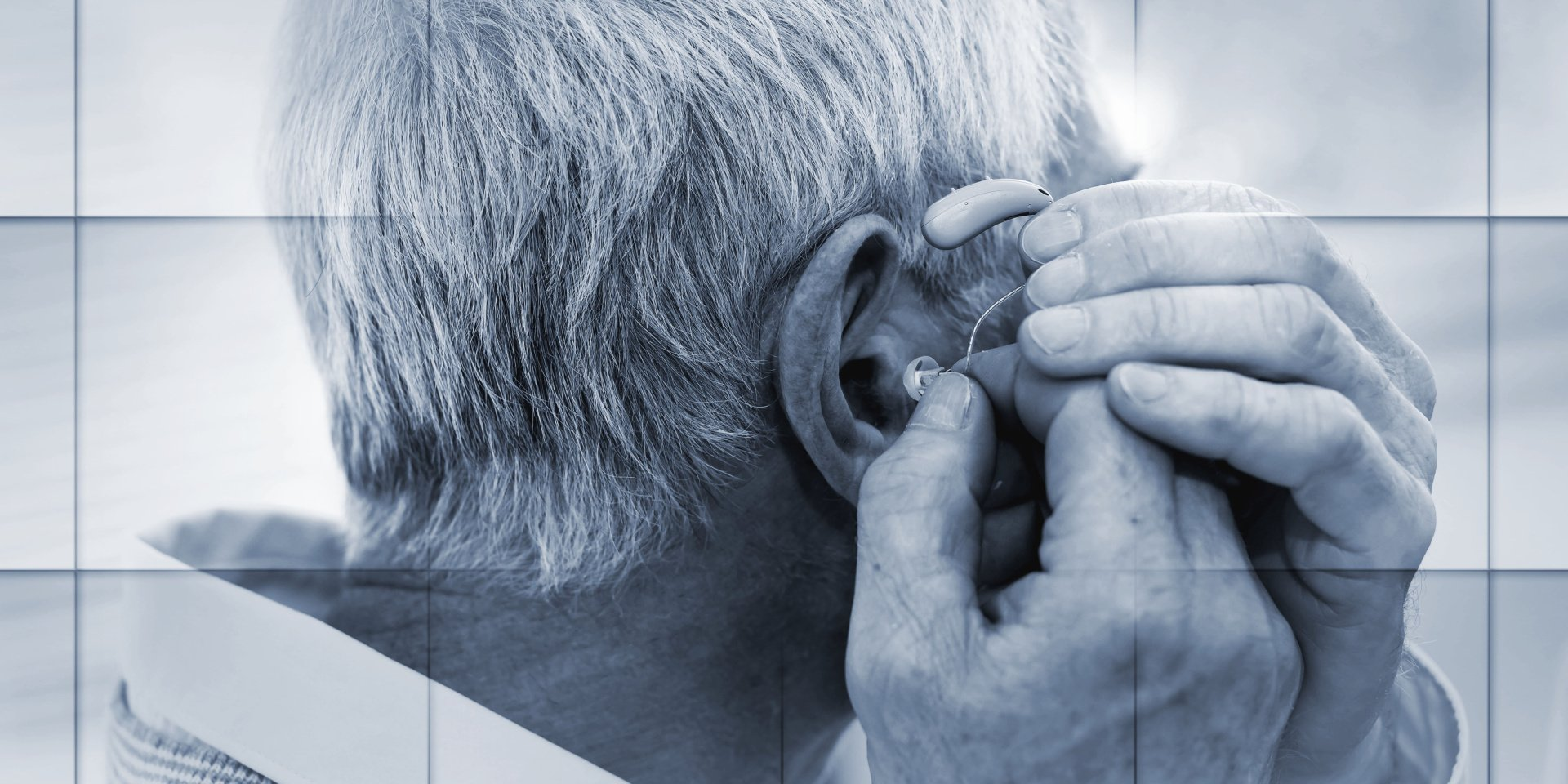 A man is putting a hearing aid in his ear.