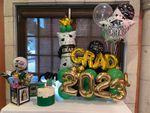 A table topped with balloons and a candle for a graduation party.