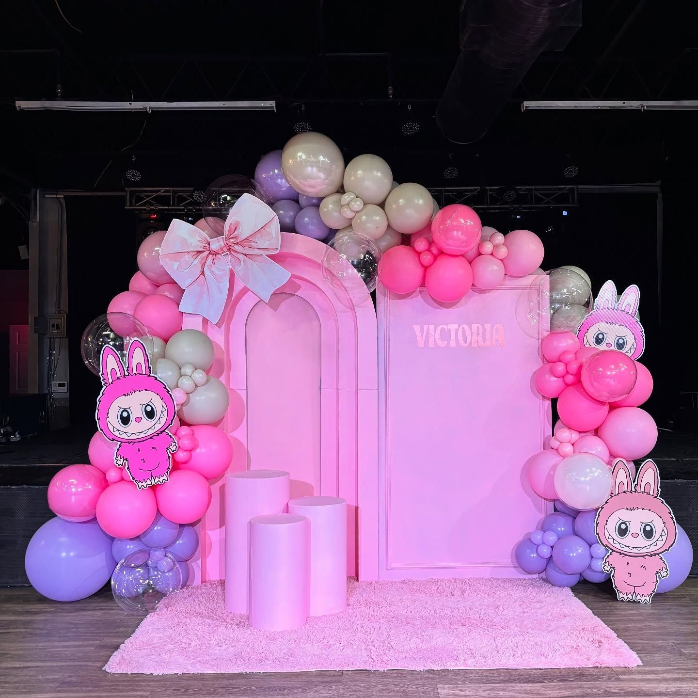 A pink wall with balloons and a bunny on it
