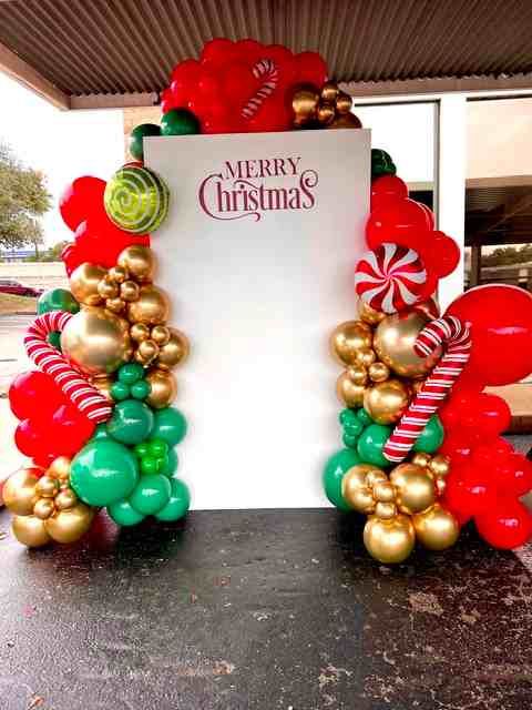Red, gold, green and candy cane balloons are in front of a Christmas backdrop.