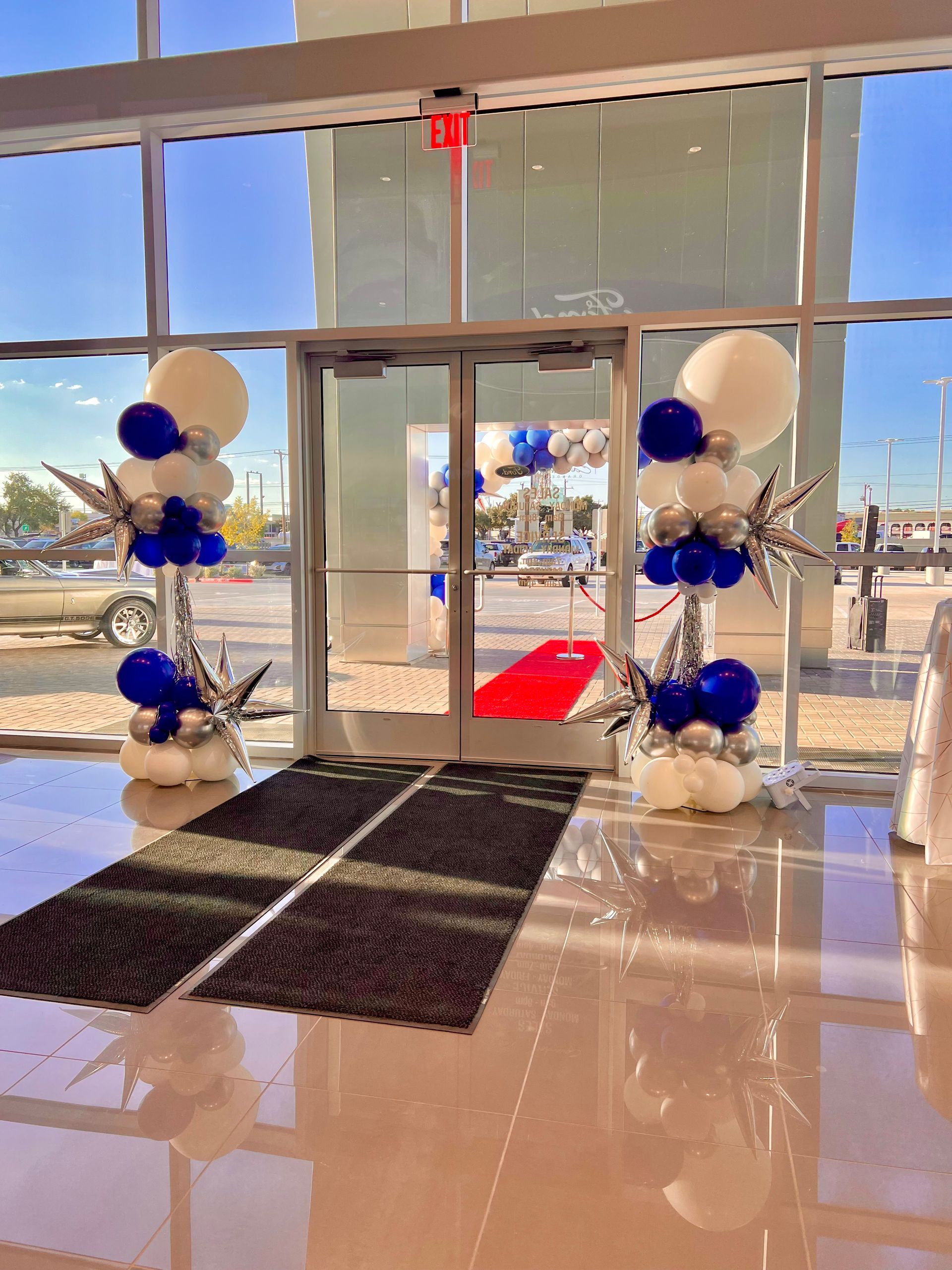 A lobby with balloons and a red carpet in front of a door.
