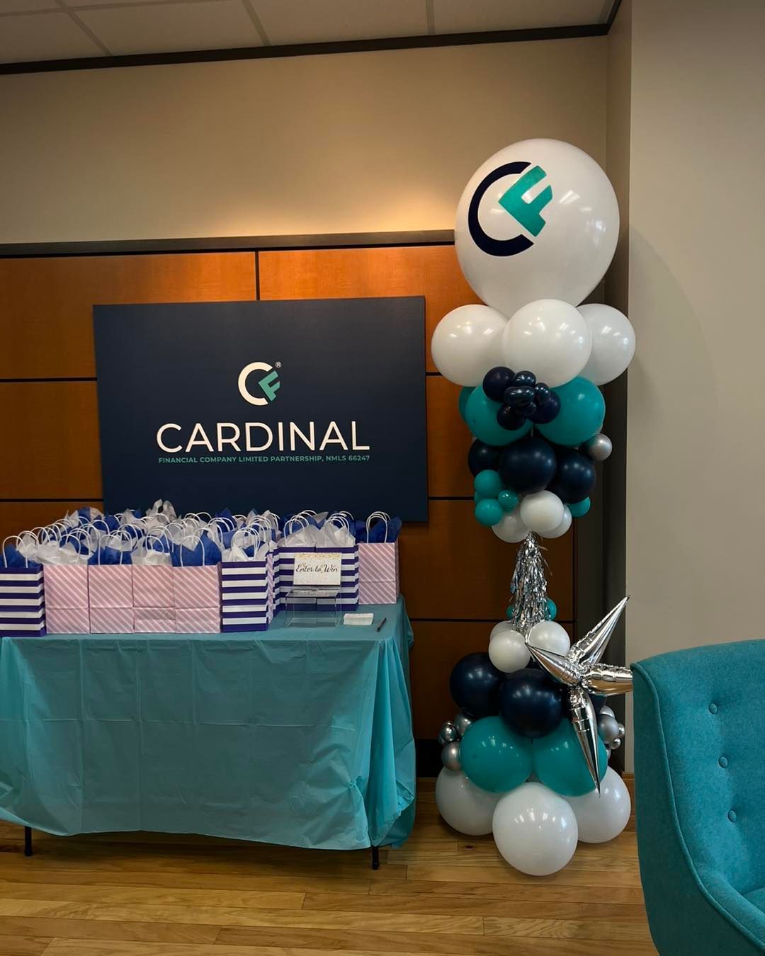 table with gift bags on it next to a balloon column with a sign saying cardinal