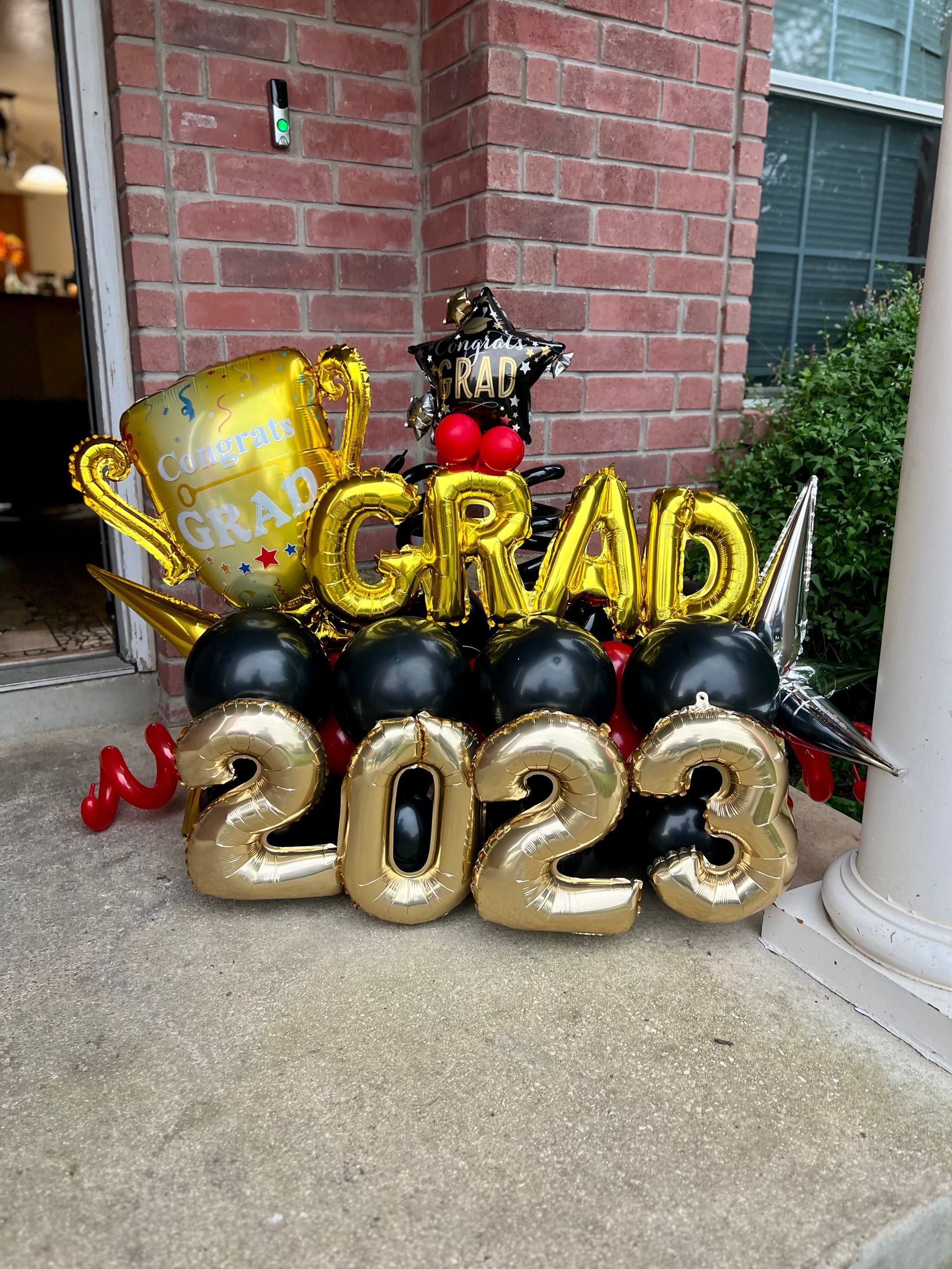 A bunch of balloons are sitting on the sidewalk in front of a brick building.