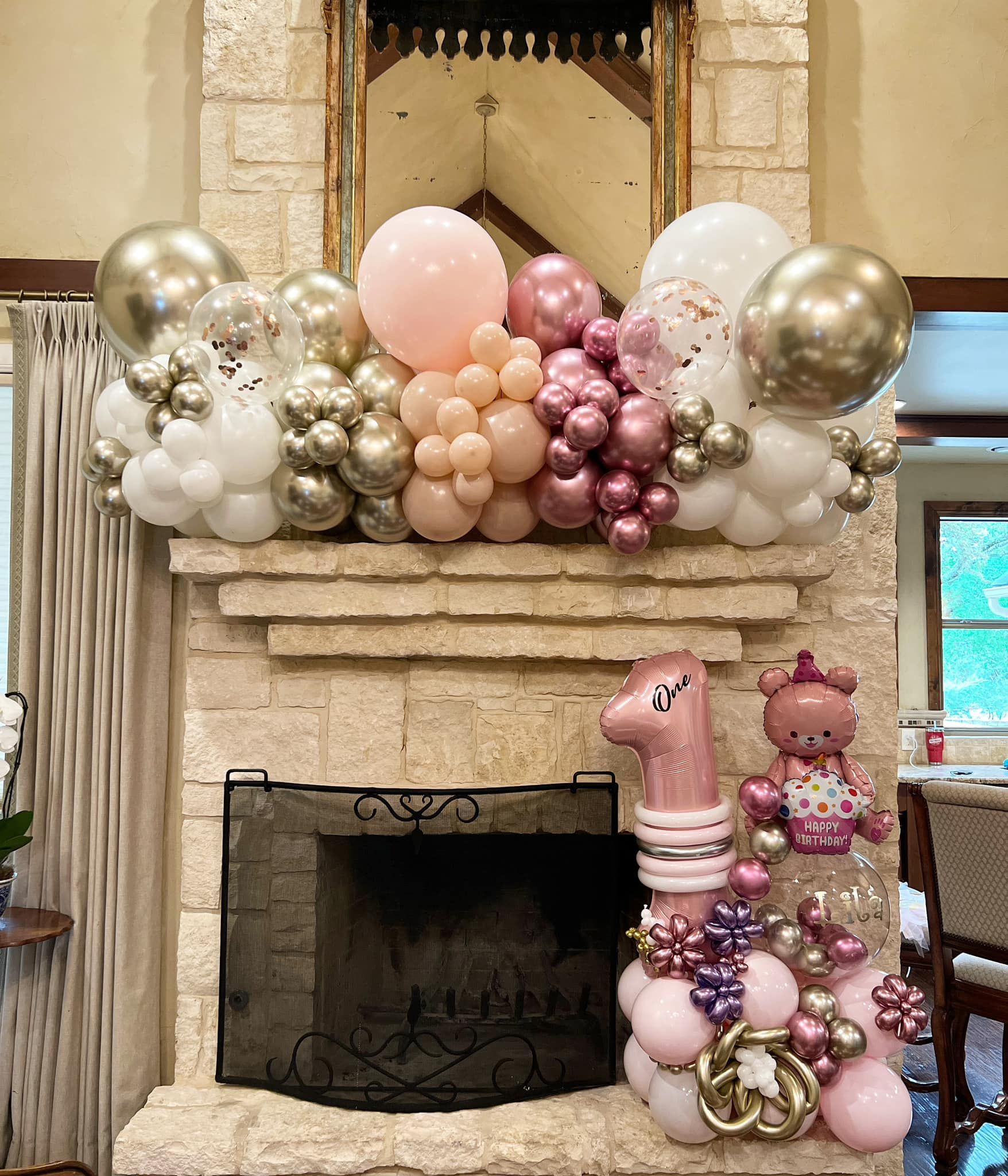 A fireplace decorated with balloons for a baby 's first birthday.