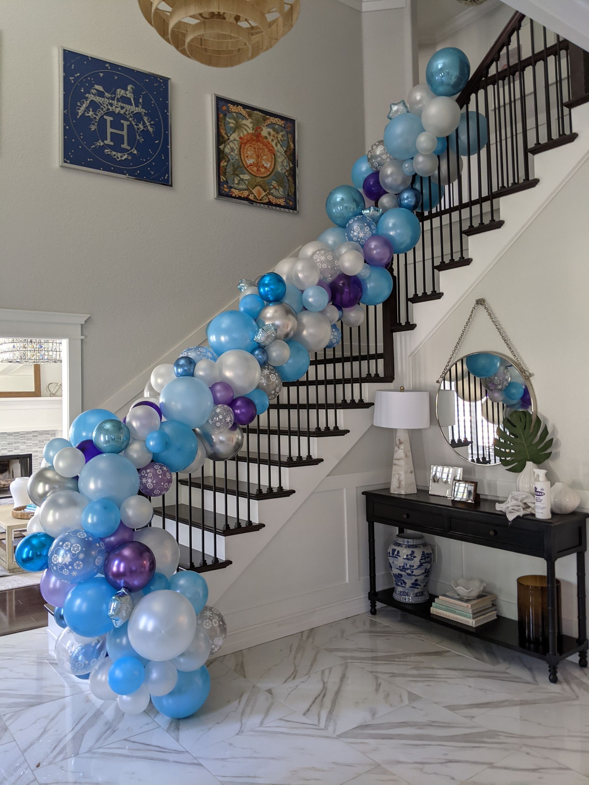 Blue and white balloon garland is on a stair railing.
