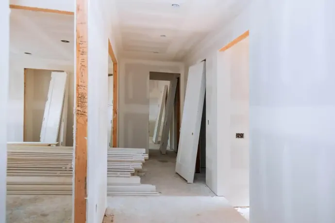 Corridoio interno in costruzione con cartongesso e porte non finite.