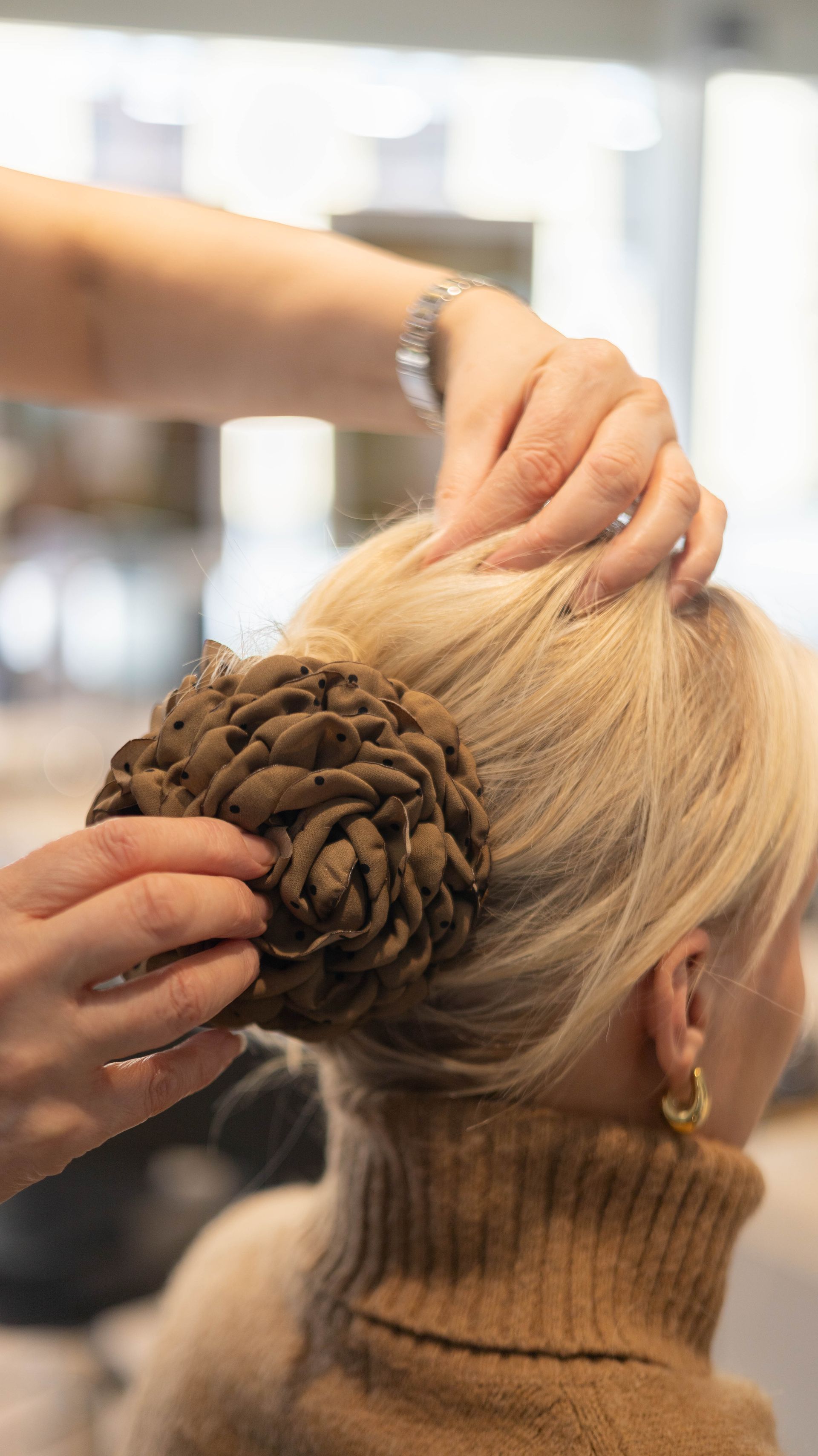Stylist arrangerer en blond opsætning med en flettet knold i en salon