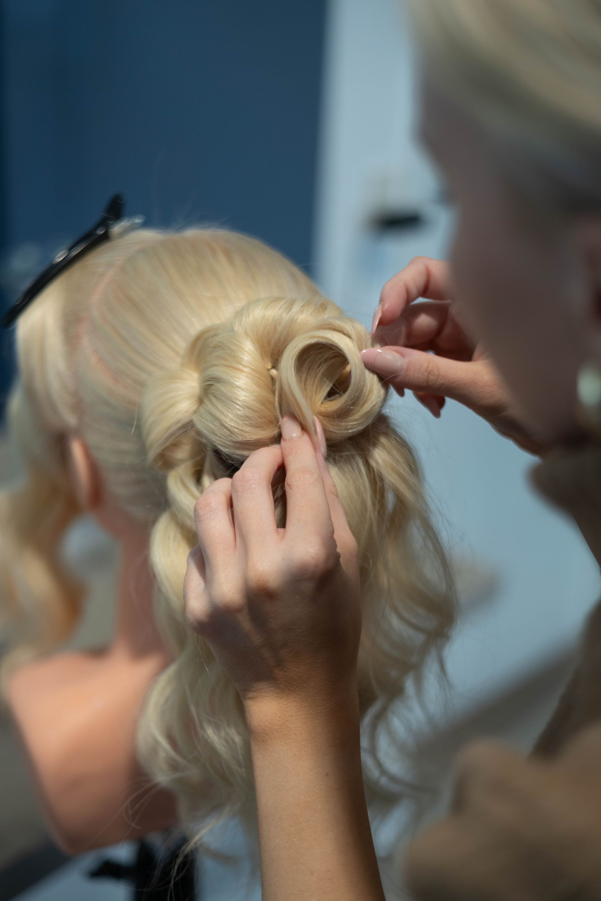 Stylist arrangerer en blond frisure med et blomstret hårtilbehør