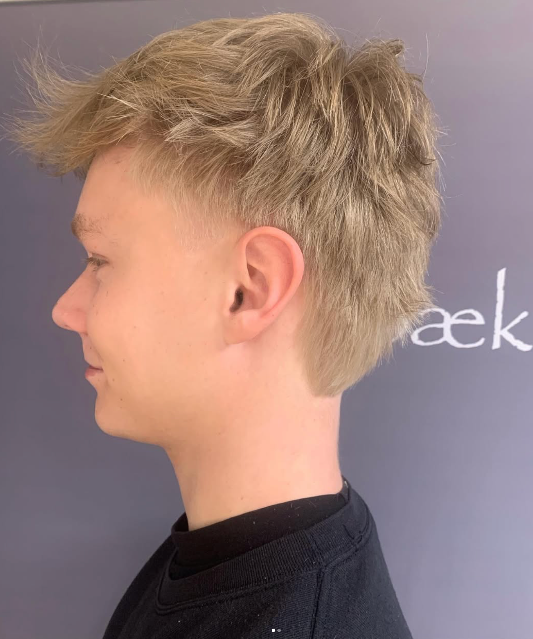 Profilbillede af en kort blond klipning med falmede sider mod en grå baggrund
