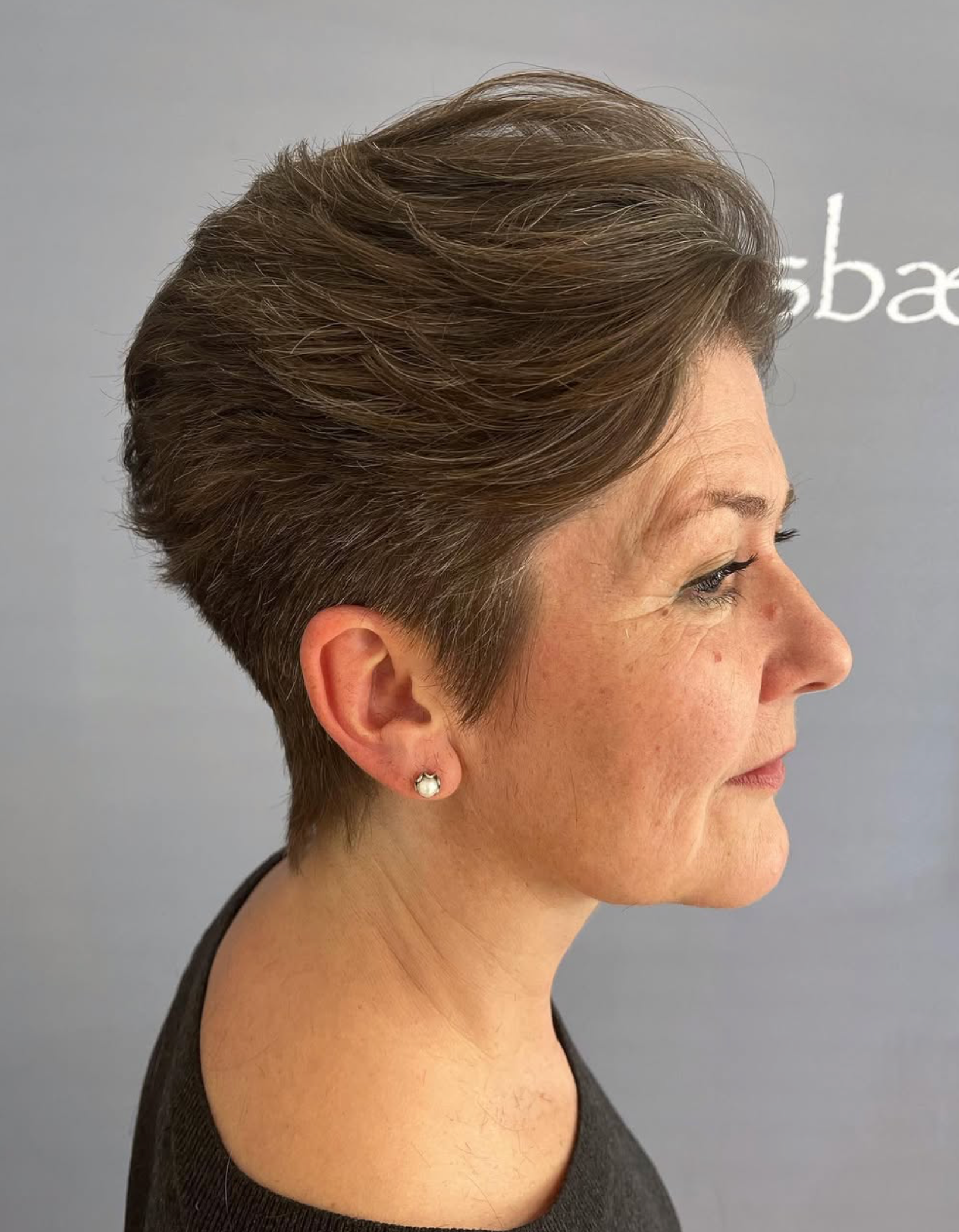 Sideprofil af en kvinde med kort brunt hår mod en grå baggrund