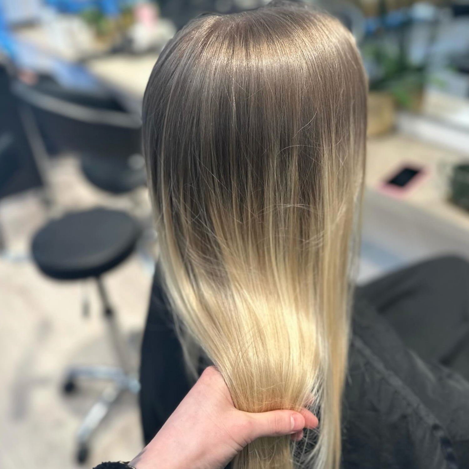 Langt, glat ombré-hår, der holdes i en salon, mørke rødder, der falmer til blonde spidser