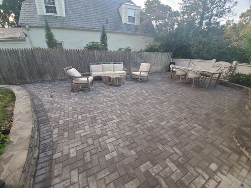 a patio with a couch and chairs in front of a house