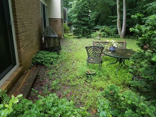 a patio with a table and chairs in front of a brick house .