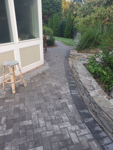 a stool sits on a brick walkway next to a stone wall