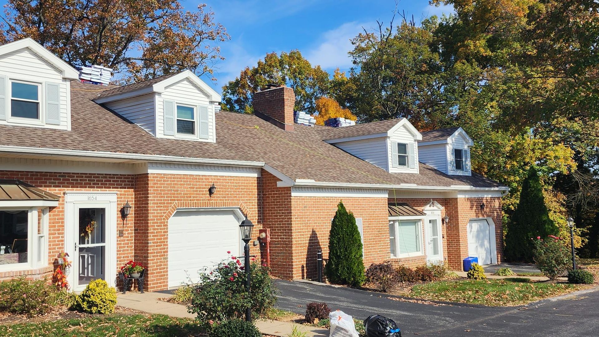 A brick house with two garages and a dog in front of it.