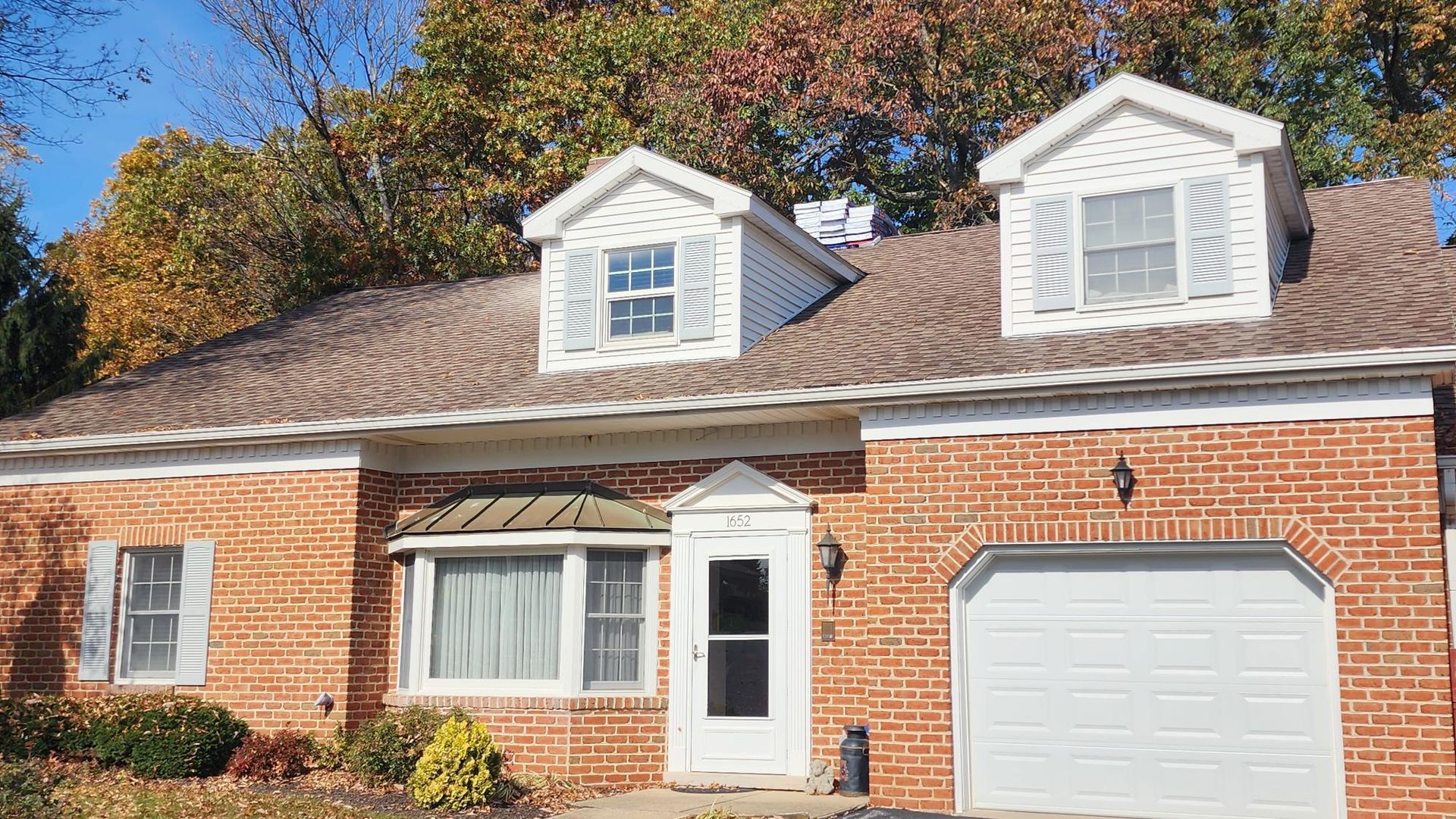 A brick house with a white garage door and white shutters.