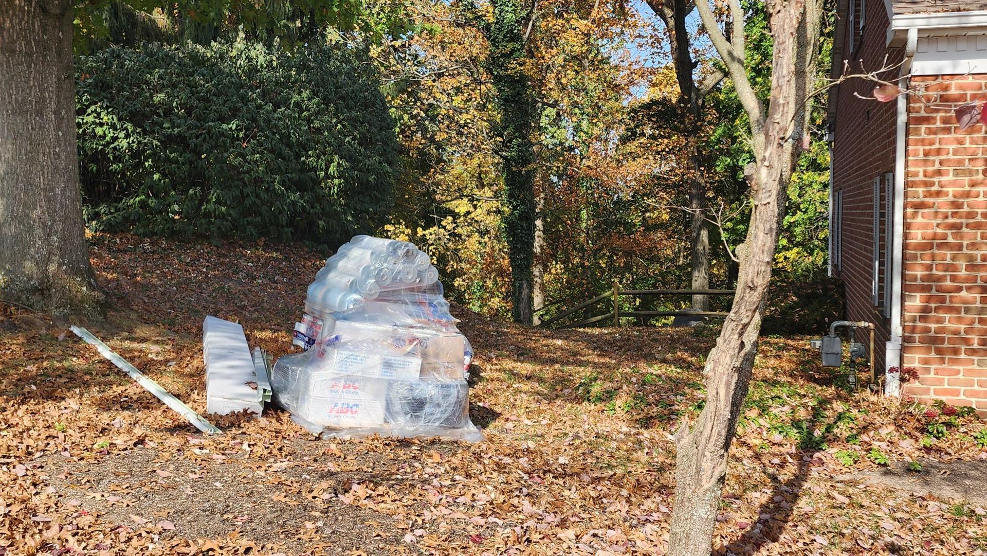 A pile of boxes sitting on top of a pile of leaves in front of a brick building.