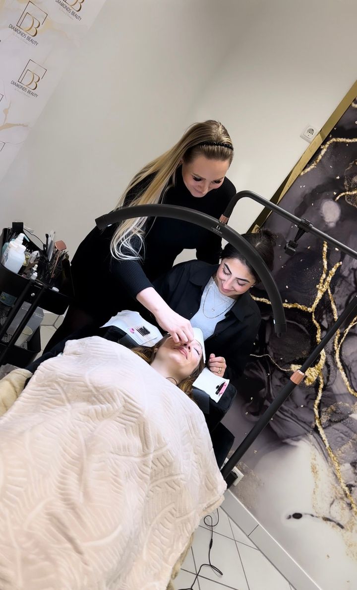 Zwei Frauen arbeiten in einem Salon an den Wimpern einer Frau