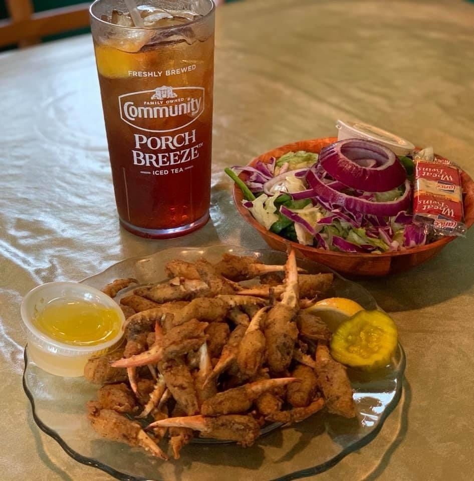 Glass of Porch Breeze drink beside fried shrimp and salad on a table, with dipping sauce and lemon slice