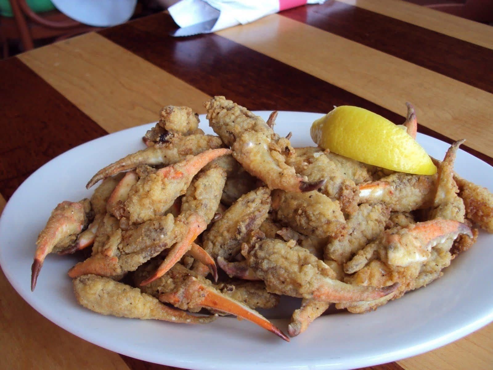 Plate of seasoned fried crabs with a lemon wedge on a wooden table.