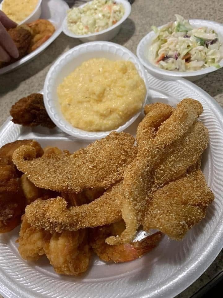 Plate of fried seafood with hush puppies, macaroni and cheese, and coleslaw on a table