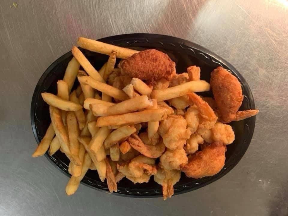 Plate of French fries with chicken tenders and fried seafood on a black tray