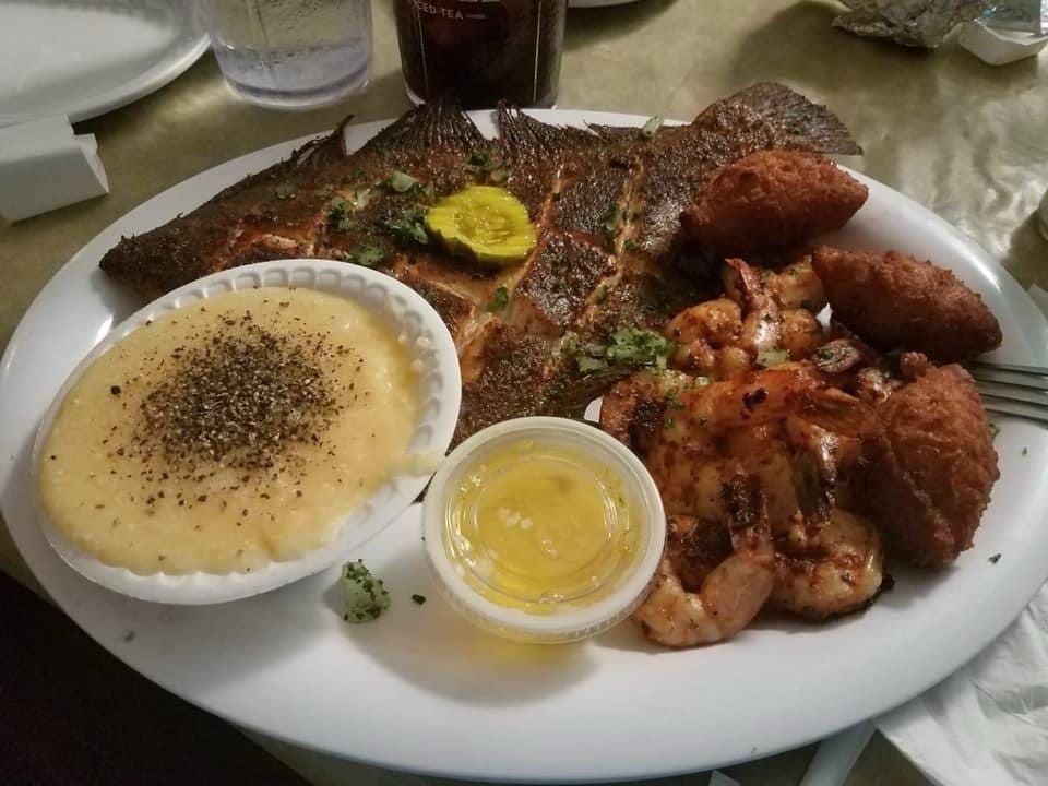 Plate of grilled fish with rice, fried plantains, and sides on a restaurant table