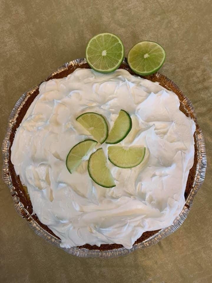 Lime-topped white frosted pie in a crust, decorated with lime slices on top
