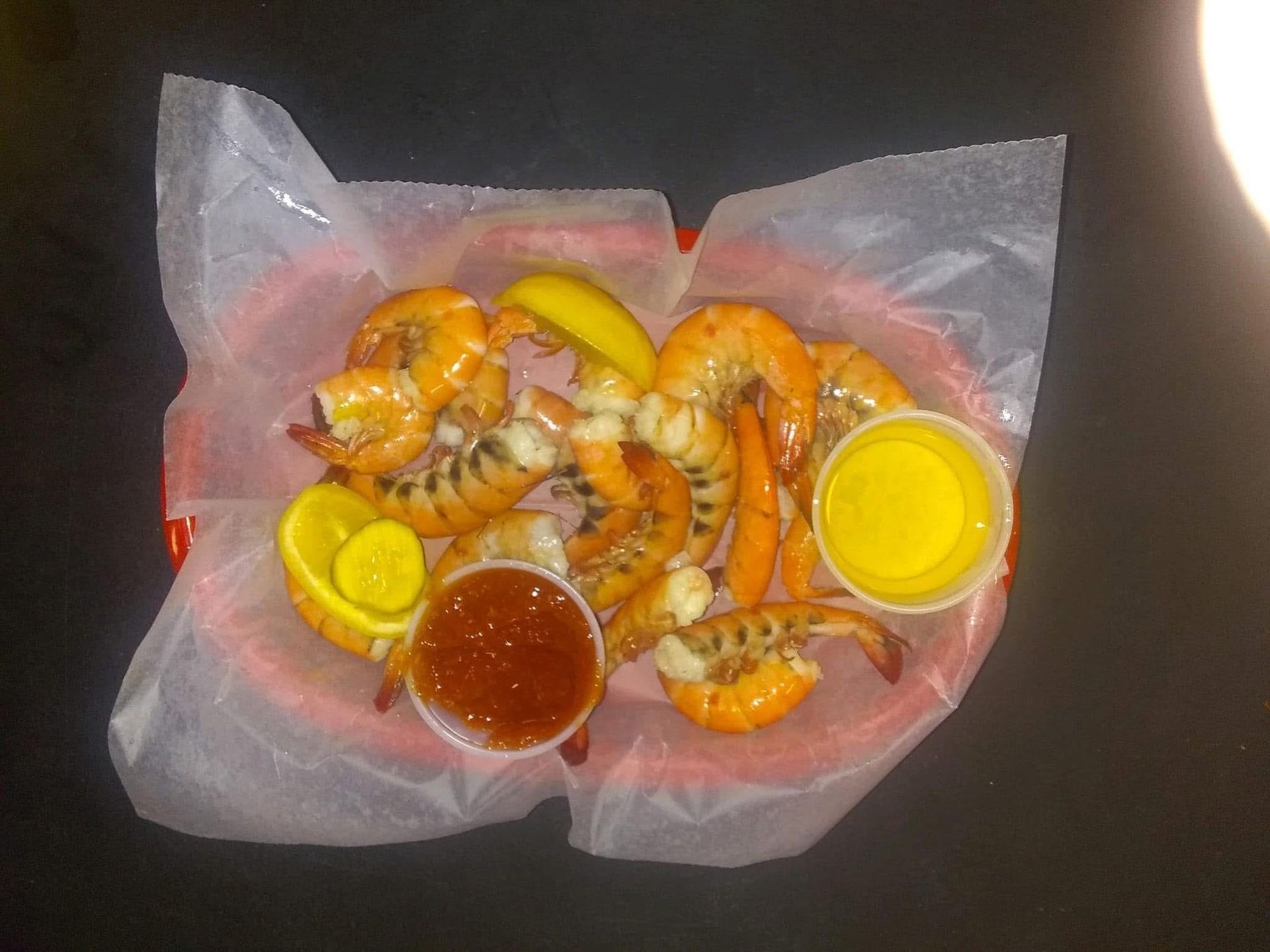 Seafood boil with shrimp, corn, potatoes, lemon wedges, and dipping sauces on parchment paper
