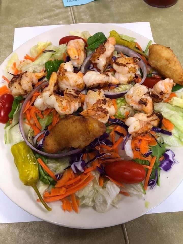 Grilled shrimp salad with colorful vegetables, peppers, purple cabbage, and fried plantains on a white plate