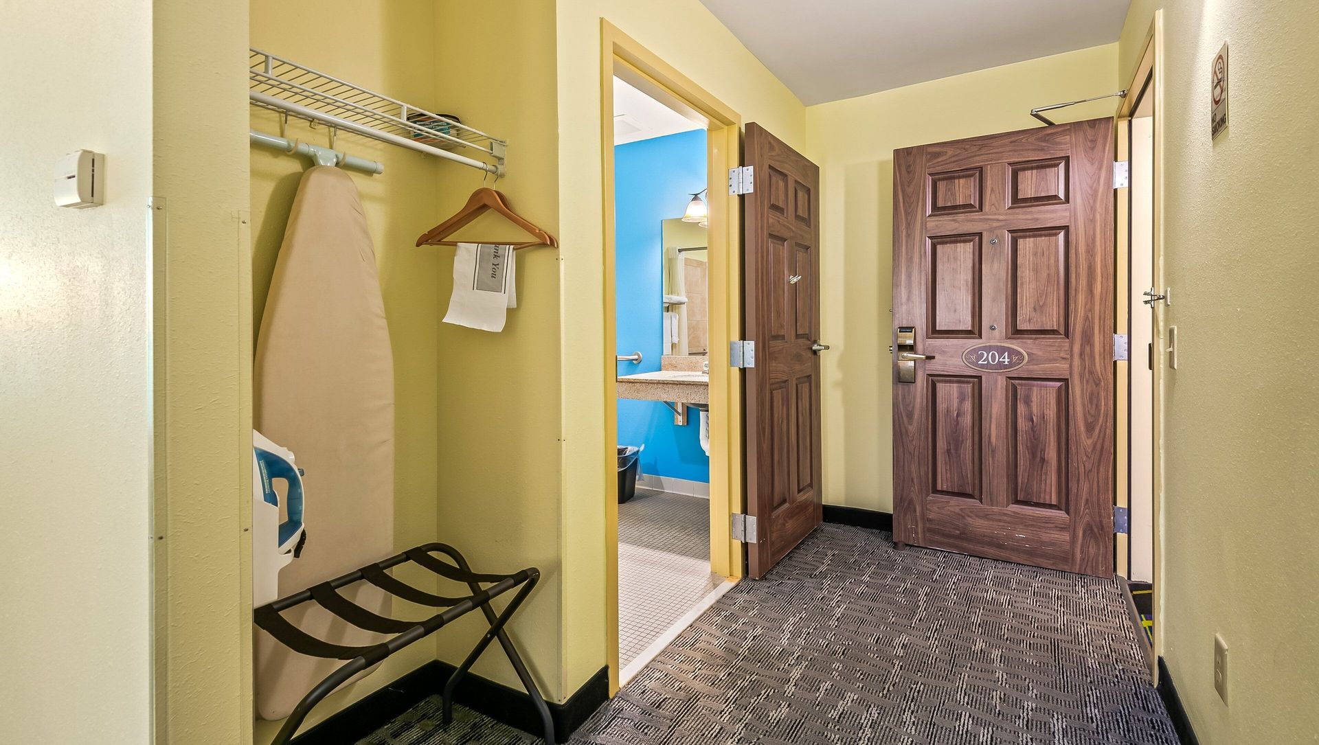 Hallway with coat rack, bench, patterned carpet, and open door leading to a blue room and closed wooden closet doors