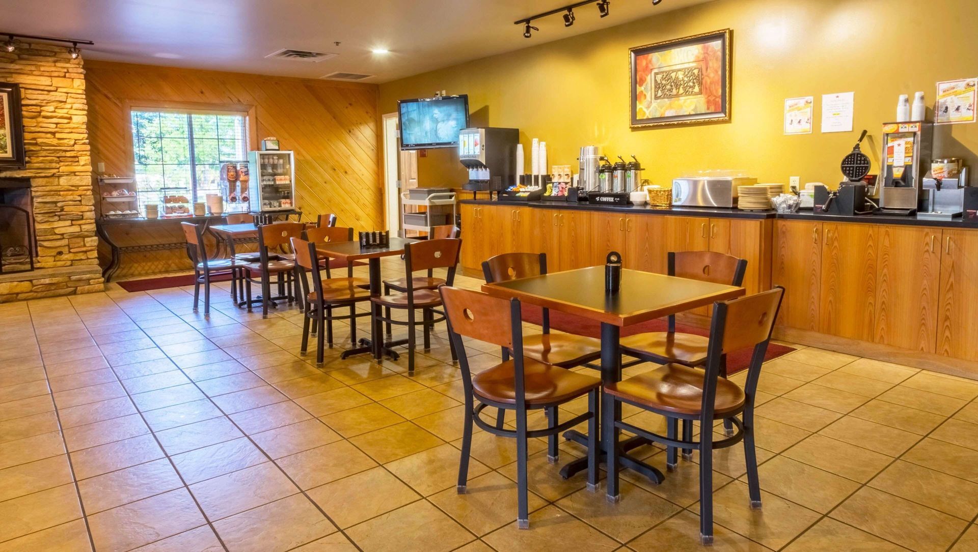 Cozy café interior with wooden tables, tiled floor, and a long counter under warm yellow walls