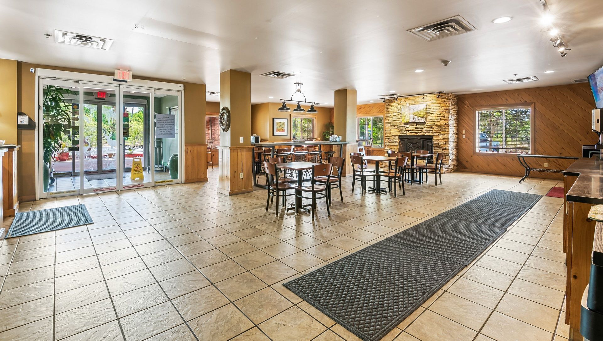 Bright lobby with tiled floor, glass entrance, seating area, and walls with artwork and plants