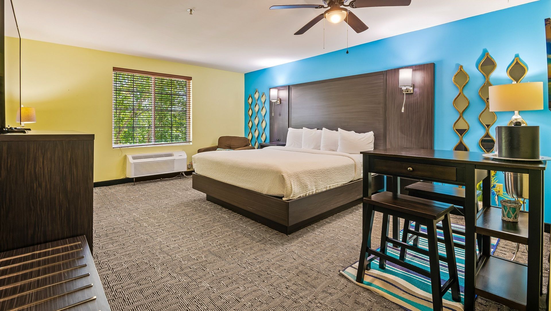 Modern bedroom with a large bed, patterned carpet, blue accent wall, and decorative mirrors