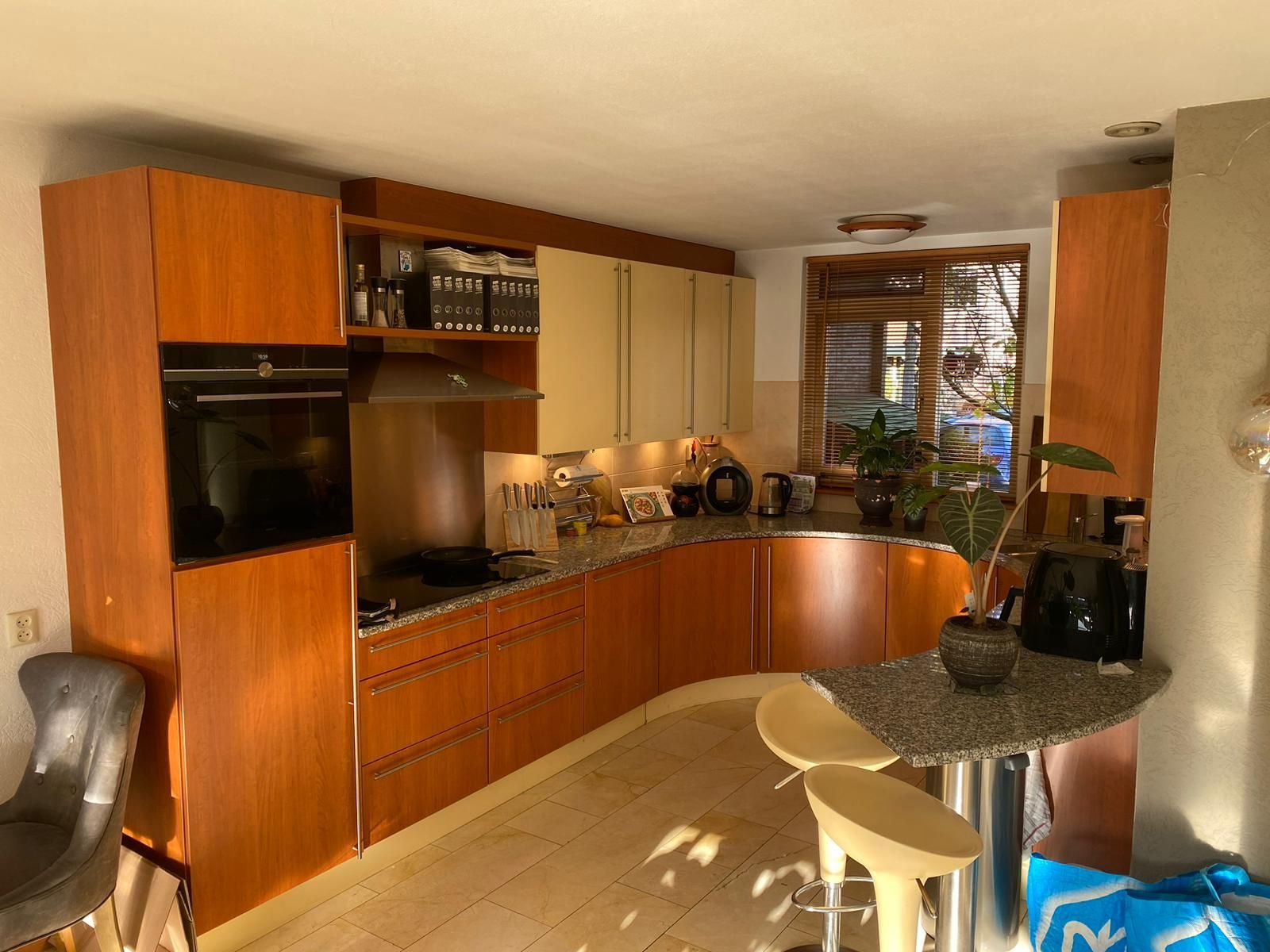 Keuken wrappen met houtlook kasten, granieten aanrechtbladen en een ontbijtbar.