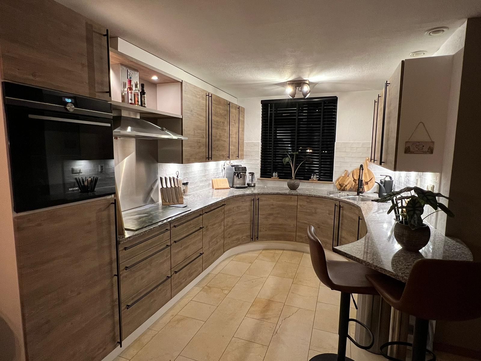 Moderne keuken wrappen met houten kasten, gebogen aanrechtbladen ontbijtbar.