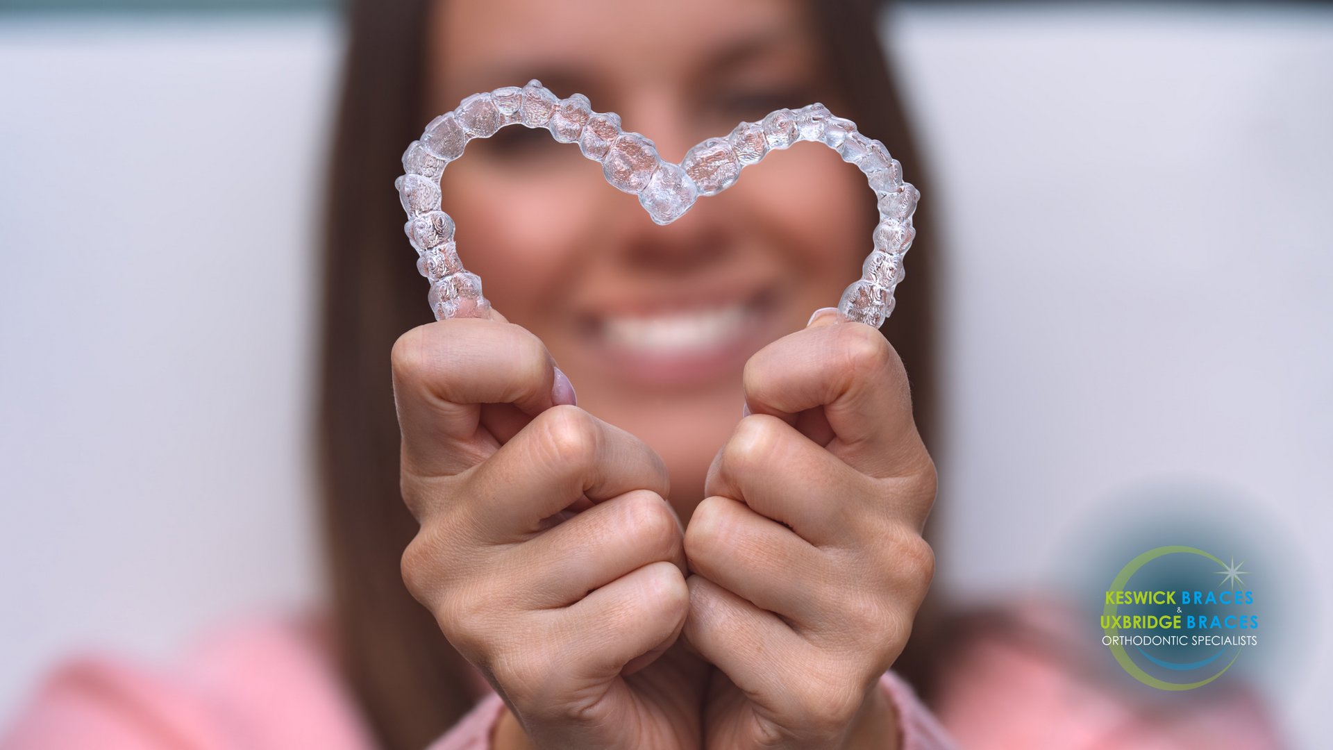 A woman is holding a heart shaped retainer in her hands.