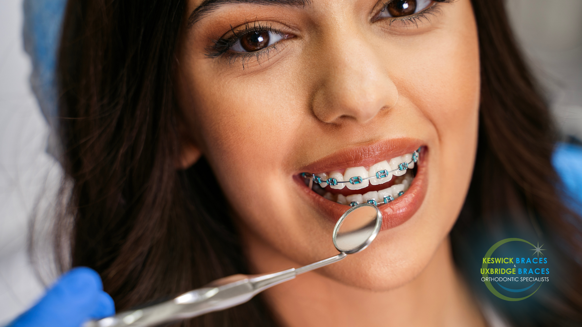 A woman with braces is getting her teeth examined by a dentist.
